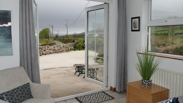 Una habitación con una puerta corrediza de vidrio que da a un espacio exterior con un banco y un muro de piedra.