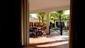 An open patio with a dining table and chairs, a pool, and palm trees. - Villa Olivia Poolside, Dive villa, 300 m from the Ocean! (Kralendijk)