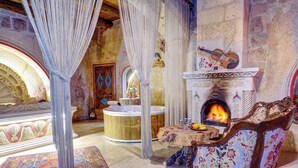 A luxurious room with a large bathtub, a fireplace, and a violin on the mantelpiece.