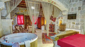 A luxurious bathroom with a large bathtub, a wooden vanity, and a red bed.