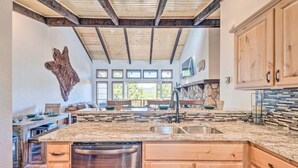 A spacious kitchen with wooden cabinets, a granite countertop, and a stone backsplash. - Spacious, Near Midtown w/ Grill+Deck+Views+Arcade (Ruidoso)