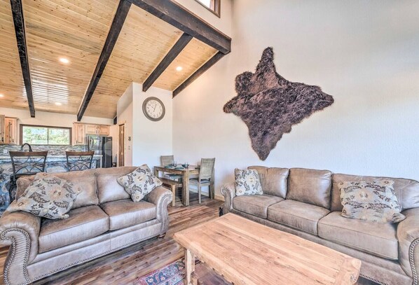 A spacious living room with leather sofas, a wooden coffee table, and a large fur wall piece.