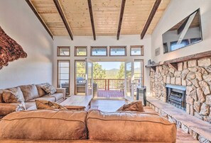 A spacious living room with a leather sofa, a stone fireplace, and a view of the outdoors.