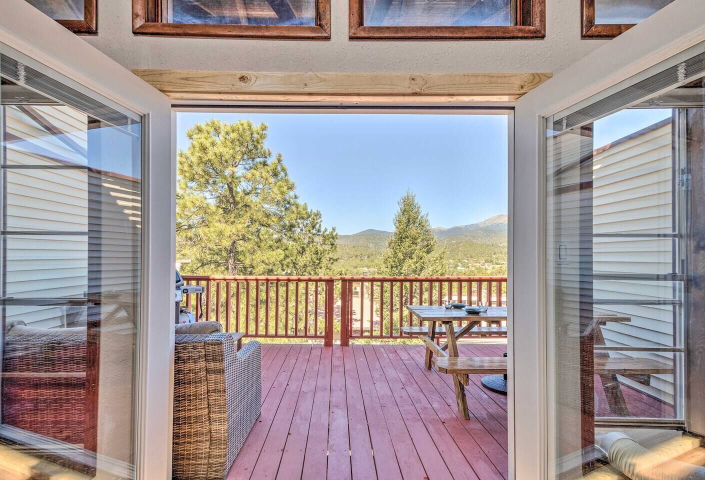 A deck with a wooden railing, a table, and chairs.