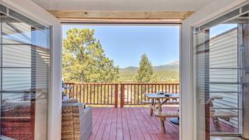 A deck with a wooden railing, a table, and chairs.