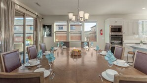 A dining room with a wooden table set for six, surrounded by chairs, with a view of the outside through large windows. - Paradise Village Resort 103: Resort View, Private Hot Tub, Short Walking distance to Resort (Santa Clara)