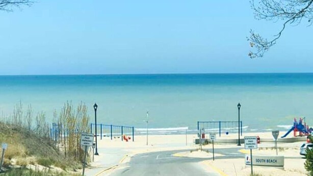 Ein Zugang zum Strand mit einem Schild, das 'South Beach' anzeigt, und einer Fußgängerquerung.