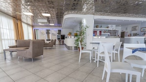 Eine moderne Hotelhalle mit Rezeption, Sitzgelegenheiten und einer Bar.