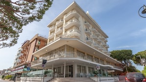 Ein mehrstöckiges Hotel mit einer markanten Hausecke, Balkonen in jeder Etage und blauem Himmel.