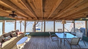 Una terraza de madera con una mesa y sillas, un sofá y una lámpara colgante.