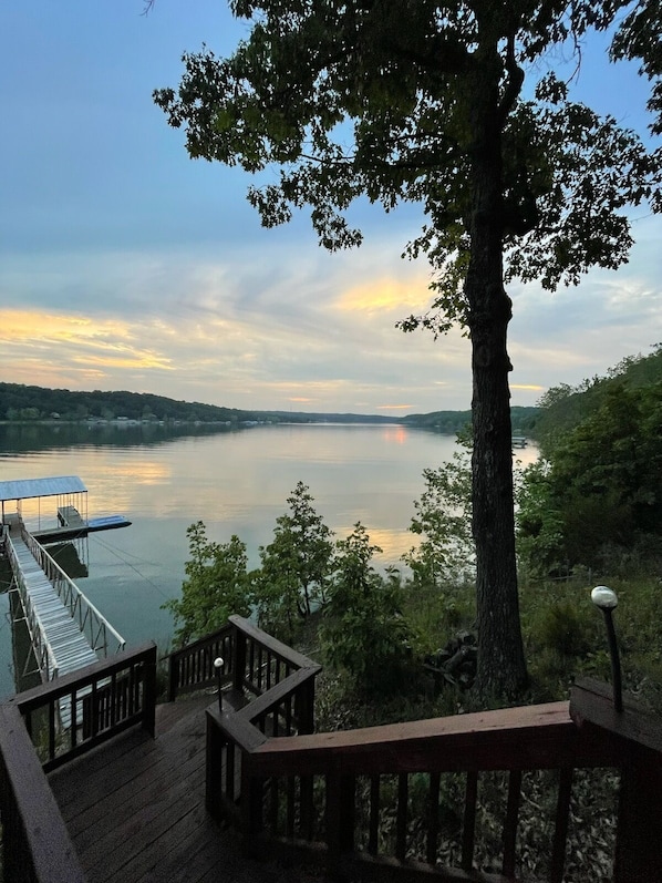 A wooden deck with a view of a calm lake and distant hills.