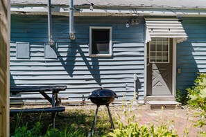 A blue house with a front door, a window, and a barbecue grill in the foreground. - Relaxed 1 BR Near Lake with Fast WiFi, Fire Pit + (Coloma)