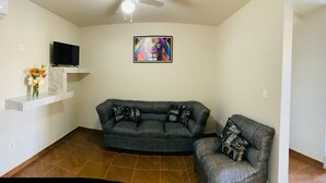 A modern living room with a gray sofa, a flat-screen TV, and a colorful abstract painting. - Hotel Santa Cruz Residencial (San Luis Rio Colorado)