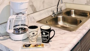 A kitchen with a coffee maker, two coffee mugs, and a packet of coffee pods on the counter. - Hotel Santa Cruz Residencial (San Luis Rio Colorado)
