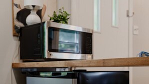 Une petite cuisine équipée comprenant un four à micro-ondes, un petit réfrigérateur et un plan de travail en bois.