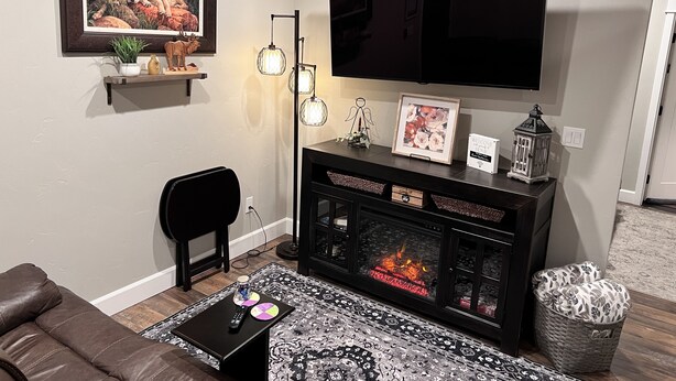A living room with a fireplace, a television mounted on the wall, and a cozy seating area.