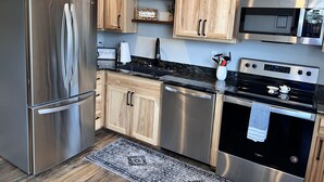 A modern kitchen with stainless steel appliances, wooden cabinets, and a granite countertop. - Cozy studio located near  Marina, hiking trails & downtown Sequim. Pet friendly. (Sequim)