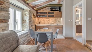 A cozy kitchen with stone walls, a wooden ceiling, and a dining area with a table and chairs. - Palace Luxury Retreat - Old Town (Split)
