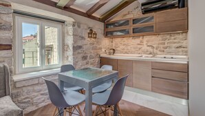 A modern kitchen with stone walls, wooden cabinets, and a glass dining table. - Palace Luxury Retreat - Old Town (Split)