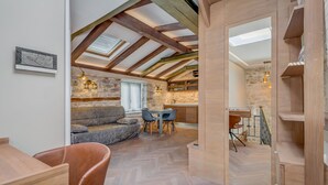 A cozy loft-style room with exposed wooden beams, a stone wall, and a herringbone-patterned floor. - Palace Luxury Retreat - Old Town (Split)