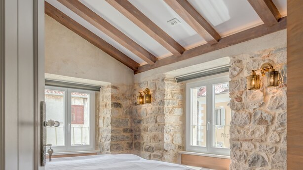 A bedroom with a wooden ceiling, stone walls, a bed, and a window with a view. - Palace Luxury Retreat - Old Town (Split)