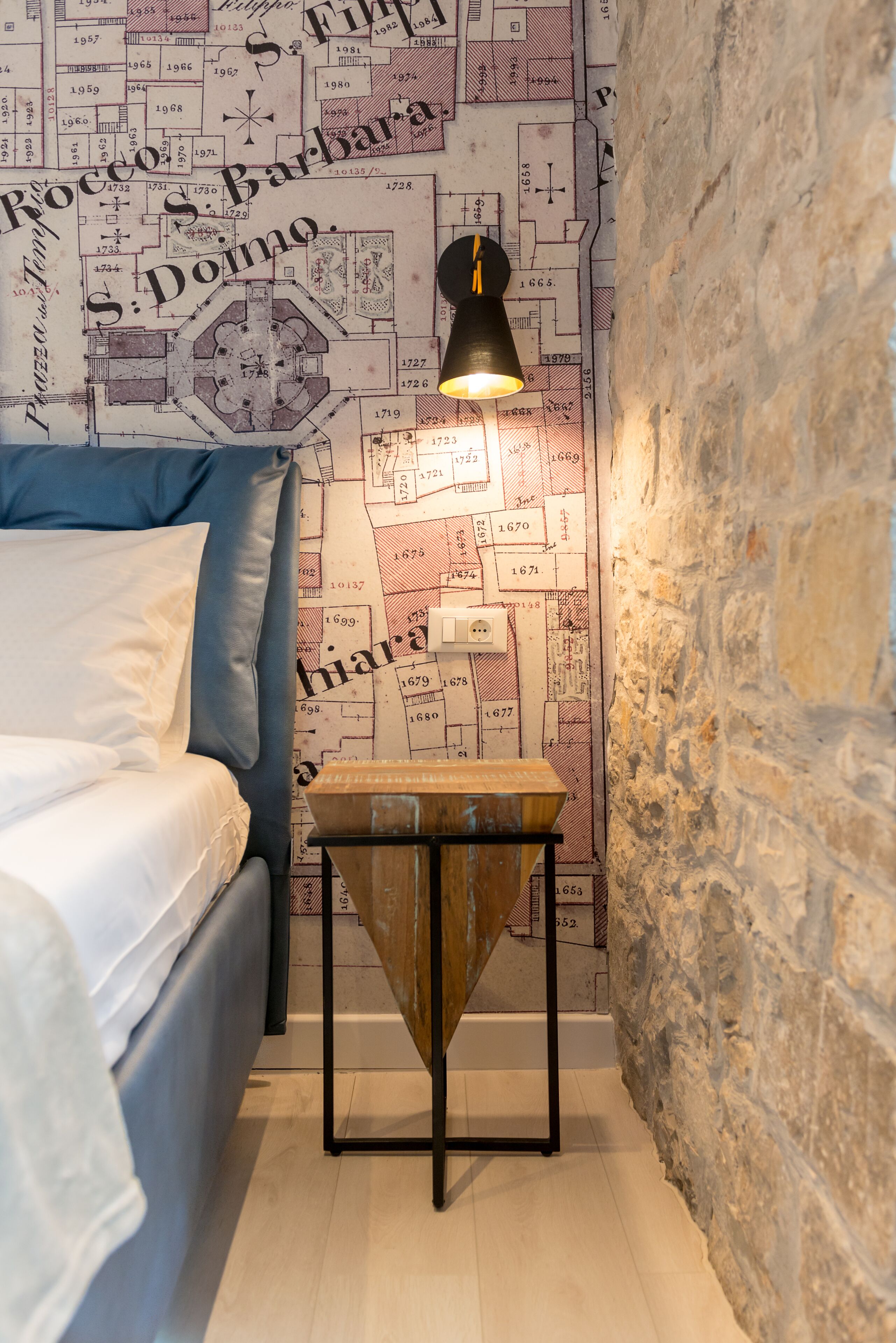 A bedroom with a bed, a nightstand, and a wall map.