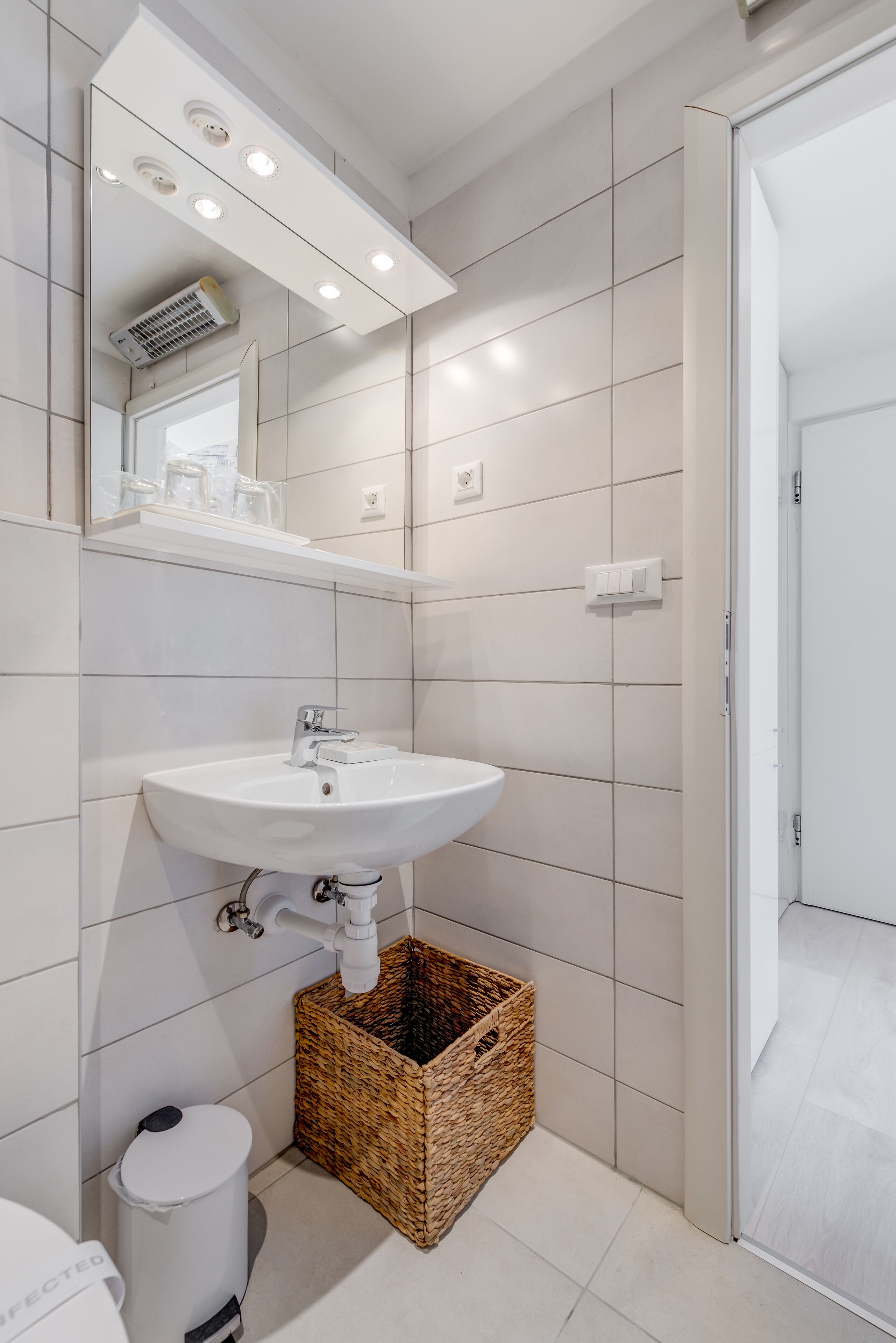 A modern bathroom with a white sink, a mirror, and a tiled floor.