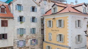 A courtyard with outdoor seating, stone buildings, and a sign reading "Plaza Marchi". - Palace Luxury Retreat - Old Town (Split)
