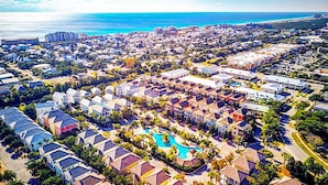 Ein Resort mit mehreren Gebäuden, einem Schwimmbecken und einem Strand im Hintergrund.
