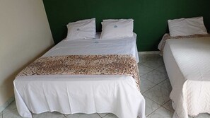 Two single beds with white bedding and a leopard print bedspread, against a green wall. - Vale Das Aguas Thermas Park (Piracicaba)