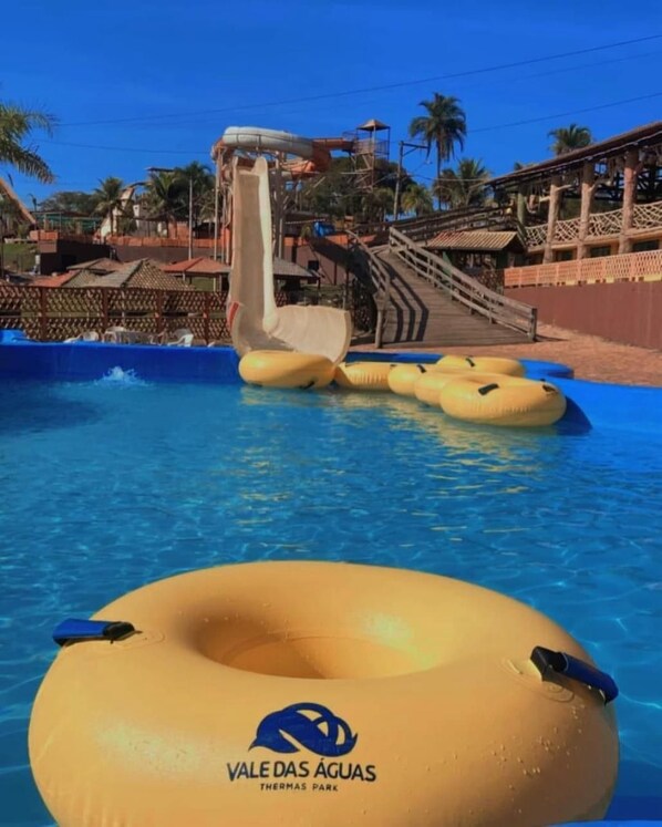 A water slide at a theme park with inflatable rafts in the pool. - Vale Das Aguas Thermas Park (Piracicaba)