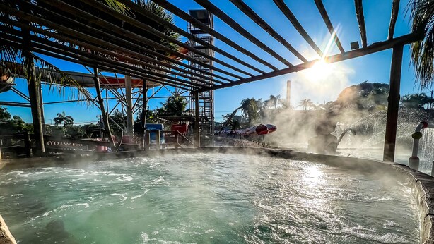 A hot spring area with a wooden pergola, a water fountain, and a view of the ocean. - Vale Das Aguas Thermas Park (Piracicaba)