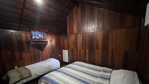 A room with wooden walls and two beds with striped bedding. - Vale Das Aguas Thermas Park (Piracicaba)
