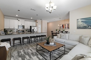 A modern kitchen with white cabinets, stainless steel appliances, and a central island with stools.