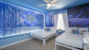 Camera da letto con due letti, una ventola a soffitto e un affresco raffigurante una foresta innevata.
