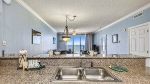 A kitchen with granite countertops, stainless steel sinks, and a hanging light fixture. - FREE Activities! Summer Deals!! Beach Access w/ Amazing 16th Floor Views! (Panama City Beach)