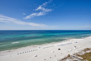 Ein Strand mit weißem Sand, klarem türkisblauem Wasser und blauem Himmel.