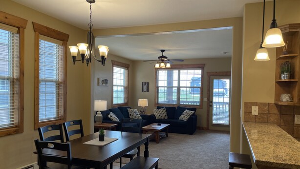 A spacious living area with a dining table, sofas, and a kitchen counter. - Buffalo Valley - Spacious Condo w/ 1 king bed and 2 queen beds (Driggs)