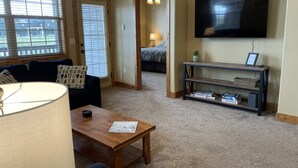A living room with a sofa, coffee table, TV, and a bookshelf. - Buffalo Valley - Spacious Condo w/ 1 king bed and 2 queen beds (Driggs)