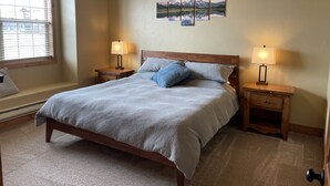A bedroom with a bed, two bedside tables, a ceiling fan, and a window with blinds. - Buffalo Valley - Spacious Condo w/ 1 king bed and 2 queen beds (Driggs)