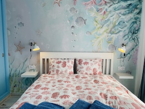 A bedroom with a bed, two bedside tables, and a wall mural.