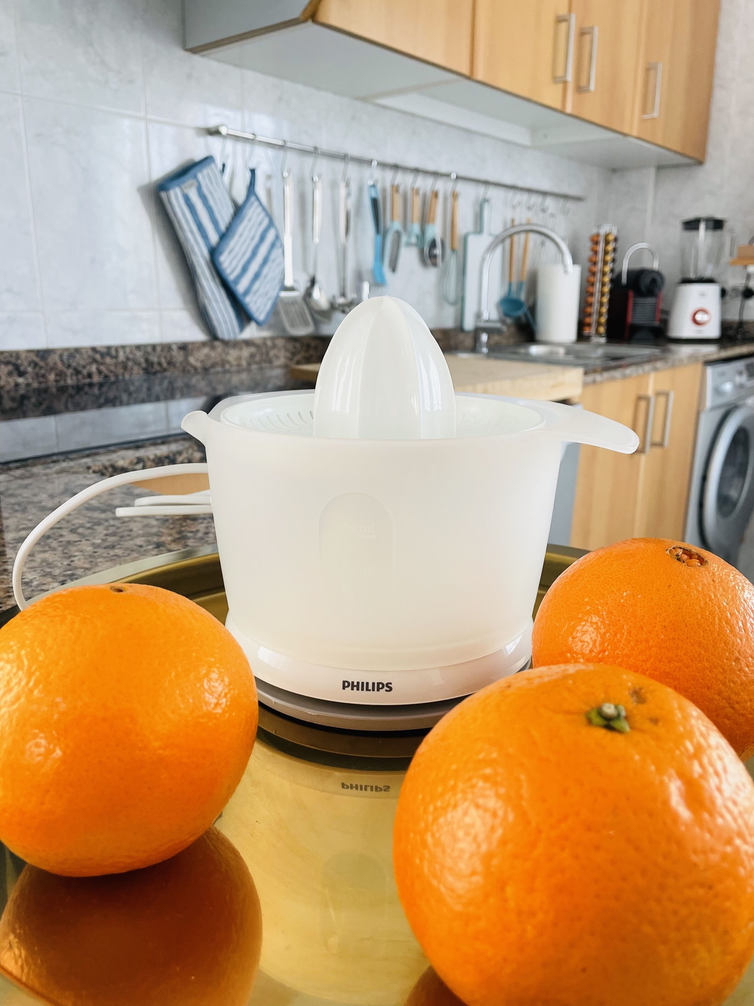 Una cocina con un exprimidor, naranjas y varios utensilios de cocina.