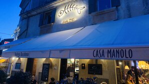 Een restaurant genaamd Casa Manolo met een witte luifel en een bord waarop staat dat het sinds 1945 in bedrijf is.