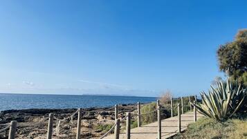 Un camí de fusta que porta a un tram de costa rocosa amb una vista clara de l'oceà.
