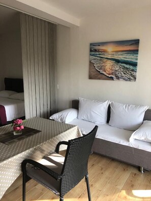 Une chambre d’hôtel équipée d’une table à manger, d’un canapé et d’un tableau représentant une scène de plage.