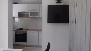 A modern kitchen with white cabinets, a microwave, an oven, and a dishwasher. - Grapevine Studio Apartment (Zdrelac)