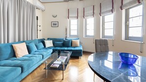 A living room with a blue sofa, a glass coffee table, and a blue bowl on a marble table. - Ideal 4 bdr Apartment in Plaka for 10! (Athens)