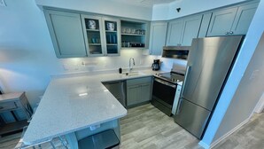 Une cuisine moderne dotée de plans de travail en granit, d’appareils électroménagers en acier inoxydable et de meubles de couleur bleu clair.