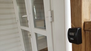Puerta blanca con teclado electrónico y paneles de vidrio.