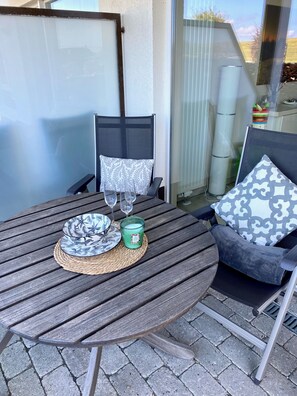 Une table de patio agrémentée d’un set de table en fibres tressées, de deux assiettes, d’une bougie et de deux verres.